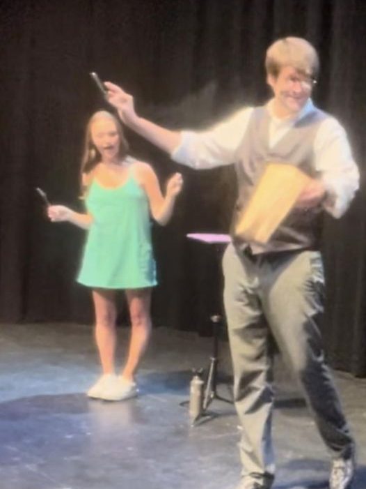 A lady in a green dress stands in amazement as Jordan Allen displays a fork that was bent seemingly by the minds of the audience